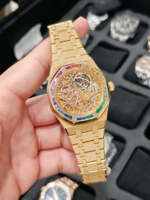 A hand displays a luxurious gold watch featuring a skeleton dial and a bezel adorned with rainbow-colored gemstones, set against a backdrop of a watch case with additional timepieces. The opulent display complements the post's bullish tone, symbolizing a successful sale and the excitement of a rising market.