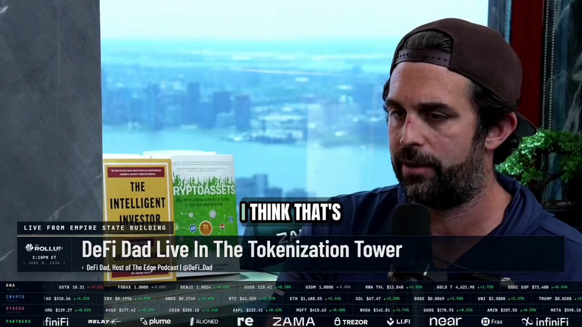 A man wearing a hat is sitting at a desk, talking into a microphone with an album titled "The Intelligent Investor" behind him. The scene takes place next to a window overlooking a cityscape. In front of the man, there are two books that appear to be related to trading or investments in some way. The image suggests that it might be a discussion or presentation about investing and related topics, with an emphasis on trading risks and the implications of sharing pools like Aave's.