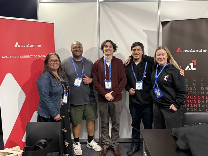 In the image, there are five people standing next to each other in front of a booth at an event. They appear to be posing for a photo or attending a conference. The group consists of four men and one woman. Each person has a name tag on their shirt, indicating that they might be part of different organizations or groups within the event.

The backdrop features a red banner with white text, which reads "AVALANCHE Avalanche Connect". This suggests that the event is related to avalanche safety or awareness, possibly organized by an avalanche rescue organization or a similar group. The presence of these name tags indicates that they are likely attending this event as part of their professional or personal interests in avalanche safety and rescue efforts.