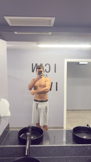 A shirtless, muscular man takes a mirror selfie in a modern bathroom while wearing white shorts, promoting engagement with the @danzsol account. The reversed text "IGN" and "VI" visible in the reflection corresponds to "GOING LIVE," reinforcing the post's invitation for viewers to drop their Solana ($SOL) wallet addresses.