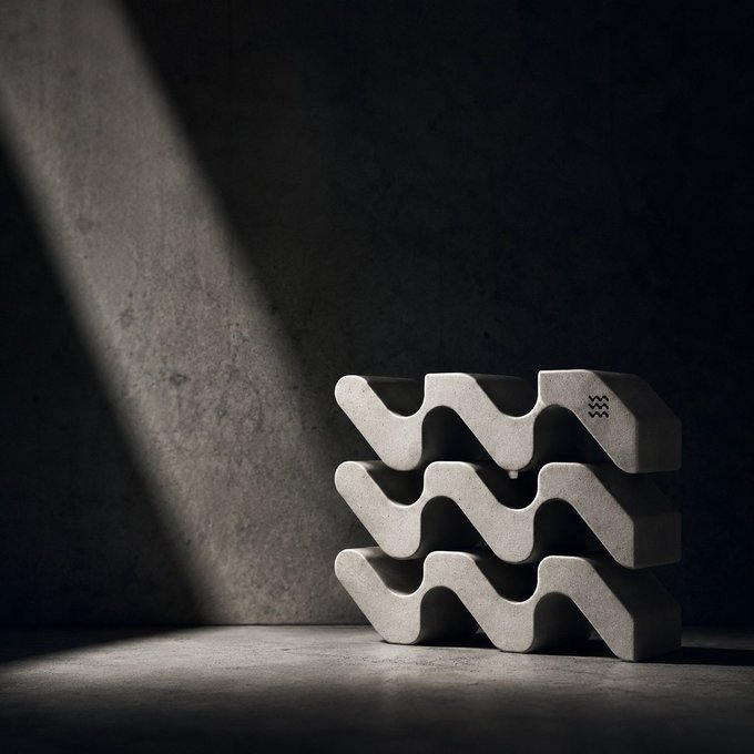A moody, artistic photograph of stacked wavy concrete decorative pieces illuminated by a dramatic shaft of light against a dark textured wall.