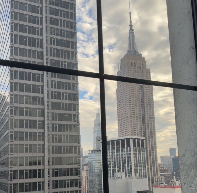 A view of the Empire State Building seen through a window in what appears to be New York City.