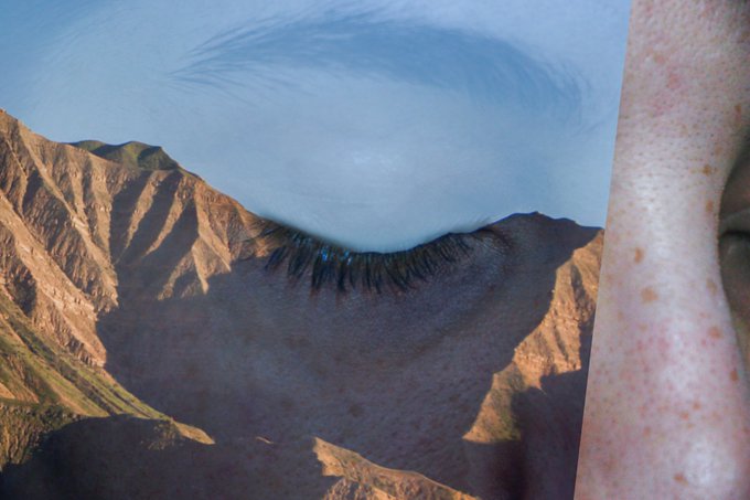 A surreal composite image featuring a close-up of a human face on the right side, merged with a mountain landscape and a swirling blue sky element.