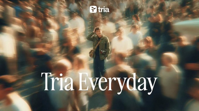 The image features a man standing in front of a crowd of people who are also looking at him. The background shows a blurred crowd of people, suggesting that this scene takes place in a busy area or event. The title "Tria Everyday" is written above and below the man's head, indicating that he is the main subject of the image.