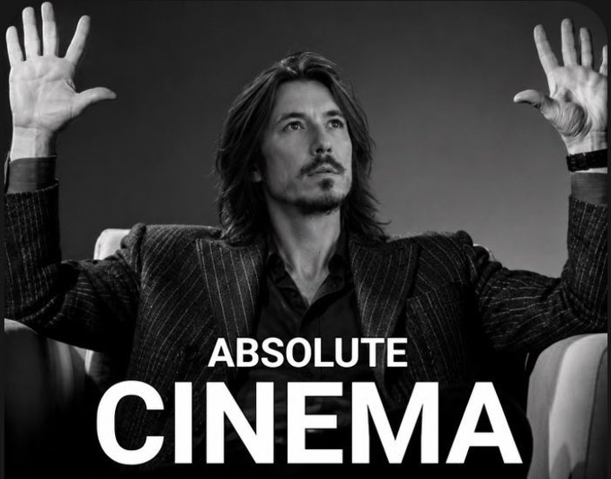 A black-and-white portrait features a man with shoulder-length dark hair and a pinstripe suit jacket, raising both hands with palms facing forward, overlaid with the text 'ABSOLUTE CINEMA'.