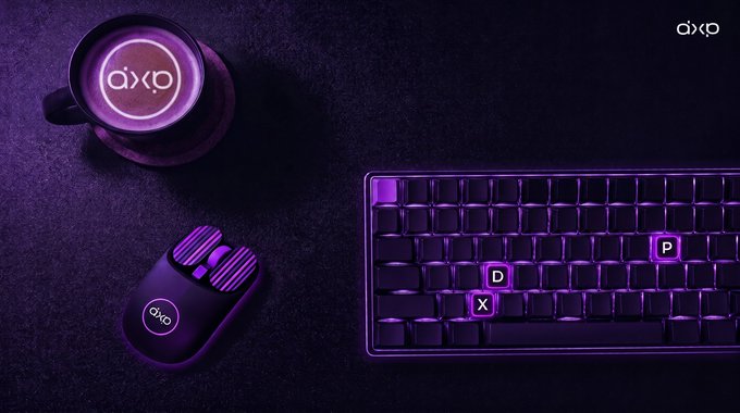 An overhead product shot of an 'axp' branded gaming setup featuring a mechanical keyboard with purple backlighting, a gaming mouse, and a beverage in a branded cup on a dark textured surface.