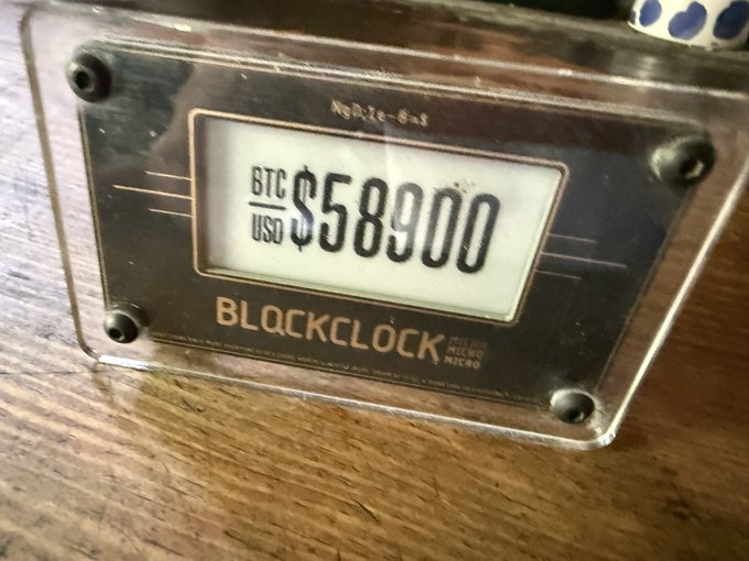 A "Blockclock Mini" device displays a BTC/USD price of $58,900, visually reinforcing the post's playful reference to Bitcoin revisiting the $58k level.