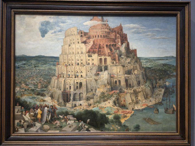 A framed painting depicting a massive, multi-tiered tower under construction by many small figures, with a harbor full of ships at its base.