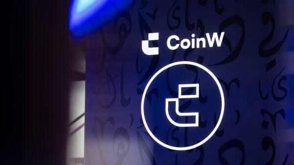 The image features a close-up of a digital screen displaying the CoinW logo, with the stylized "C" emblem prominently centered against a dark blue background with subtle decorative patterns. This visual reinforces the accompanying announcement about CoinW's expansion into TradFi perpetual contracts, highlighting the platform's branding as it broadens beyond traditional crypto markets.