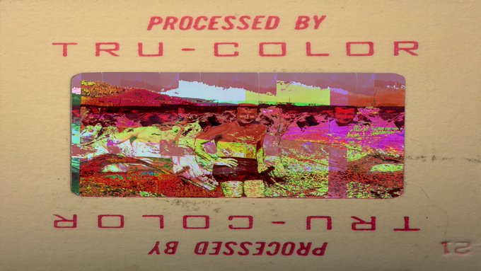 A heavily color-distorted and pixelated image on a slide or card. Red text reads 'PROCESSED BY TRU-COLOR' at the top and '12 PROCESSED BY TRU-COLOR' mirrored at the bottom, with two faint human figures visible in the center.