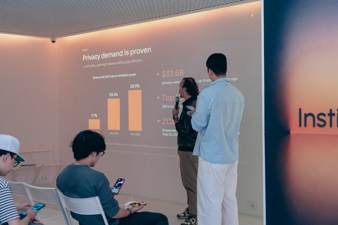 Two men present at a 'Grayscale' event with a slide titled 'Privacy demand is proven', showing a $33.6B privacy-coin market, while attendees seated in white chairs watch.