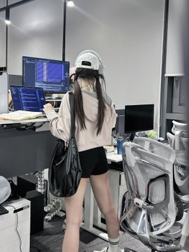 A young woman in a backwards cap and oversized hoodie works at a desk in what appears to be a converted bedroom office, surrounded by monitors and computer equipment. The image visually supports the post's narrative of someone running a data operation from home, with multiple screens and stacked hardware suggesting the 48 refurbished Mac minis mentioned in the caption, though the specific gear and numbers aren't directly visible in the photo itself.