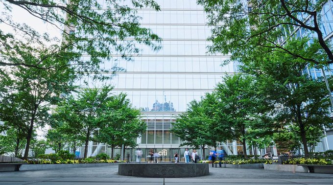 A glass-fronted Citigroup office building is shown, with several people gathered outside in the plaza surrounded by greenery. This appears to be related to the article about Citigroup preparing to launch Bitcoin custody services for institutional clients.