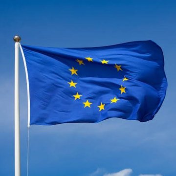 A European Union flag waves against a clear blue sky, symbolizing the continent's unified regulatory framework. The image accompanies the announcement that Ripple has secured full MiCA approval, allowing it to offer crypto services across all 30 EEA countries under this new EU-wide standard.