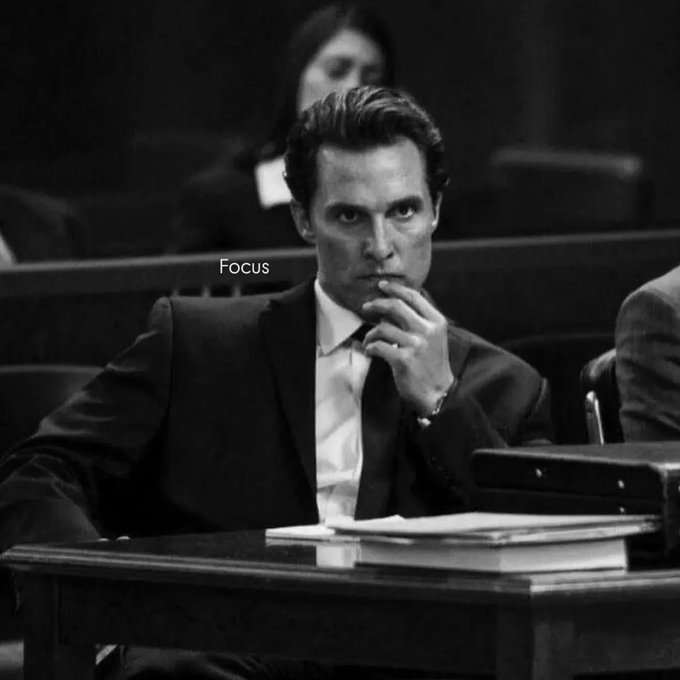 Black-and-white courtroom scene showing a suited man seated at a desk with the on-screen text “Focus.”