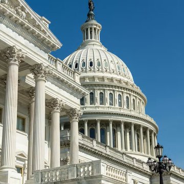 The U.S. Capitol Building stands prominently against a clear blue sky, its white neoclassical dome and Corinthian columns symbolizing federal legislative authority. The image aligns with the post's announcement of a Senate Republican crypto tax bill, representing the legislative venue where such policy changes are taking shape.