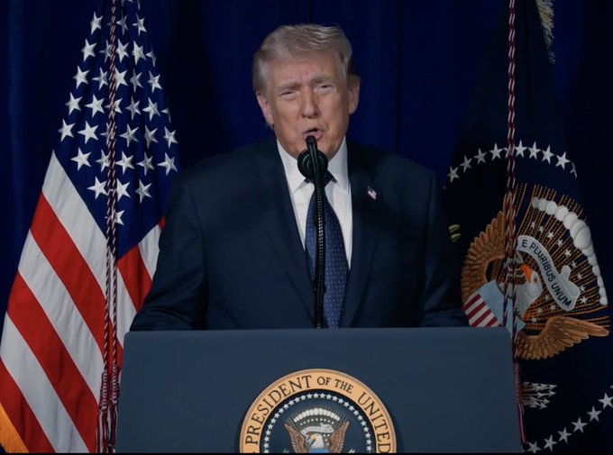 The image features a man standing at a podium, giving a speech or addressing an audience. The man appears to be wearing a suit and tie, suggesting that he might be a political figure such as President Donald Trump. The setting includes two American flags in the background, one on each side of the podium, which further emphasizes the political context of the image. Additionally, there is text in the image that reads "HUGE: Trump just FORCED the FED to answer Ripple’s master account application within 
90 DAYS." This could be a reference to the recent development involving Ripple, a cryptocurrency exchange company, and President Donald Trump's speech or address at the White House. The text suggests that the man might have made some significant announcement related to Ripple or the financial industry in general.
