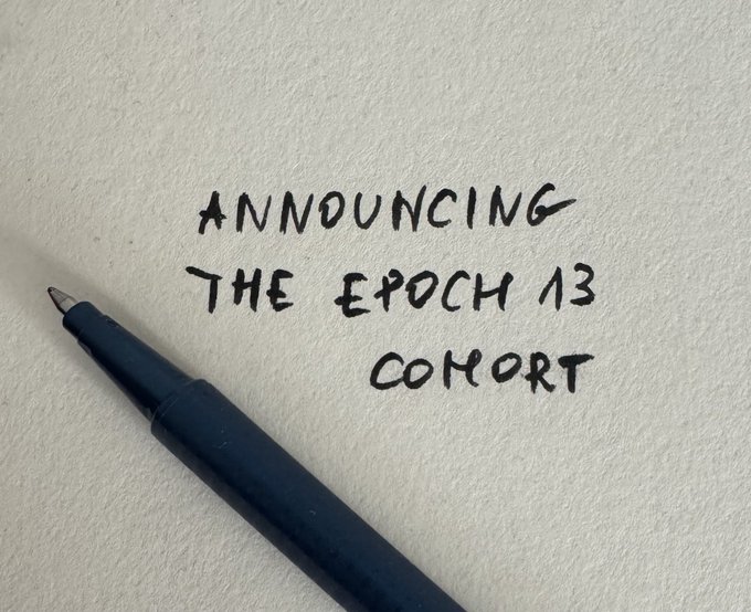 Handwritten text on white paper that reads "ANNOUNCING THE EPOCH 13 COHORT" with a dark blue pen lying next to it.