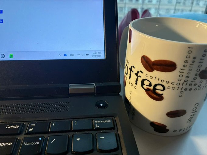 A laptop displaying 'ENG' language with a timestamp of '6:21 AM 8/23/2024' sits next to a white mug decorated with the word 'coffee' and coffee bean designs.