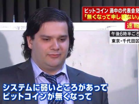 A man in a dark suit and tie appears on a Japanese news broadcast, with on-screen text referencing Bitcoin ("ビットコイン") and a missing system ("無くなって"). The image relates to the post as it appears to show Mark Karpeles, the former CEO of Mt. Gox, during one of his public statements following the infamous Bitcoin exchange collapse.