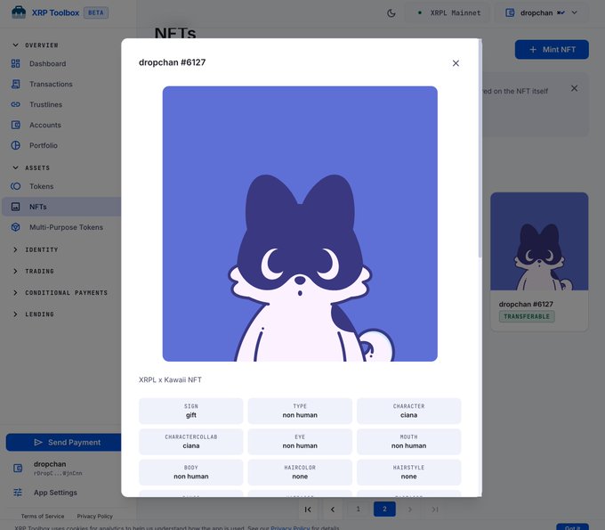 The image shows the XRP Toolbox interface displaying an NFT detail modal for "dropchan #6127," featuring a cute cartoon-style cat character with dark purple ears and a light pink body on a purple background, along with trait attributes like SIGN: gift, TYPE: non human, and CHARACTER: ciana. This demonstrates the NFT viewing capabilities mentioned in the post, showcasing how users can inspect individual NFTs and their associated traits directly within the XRP Toolbox.