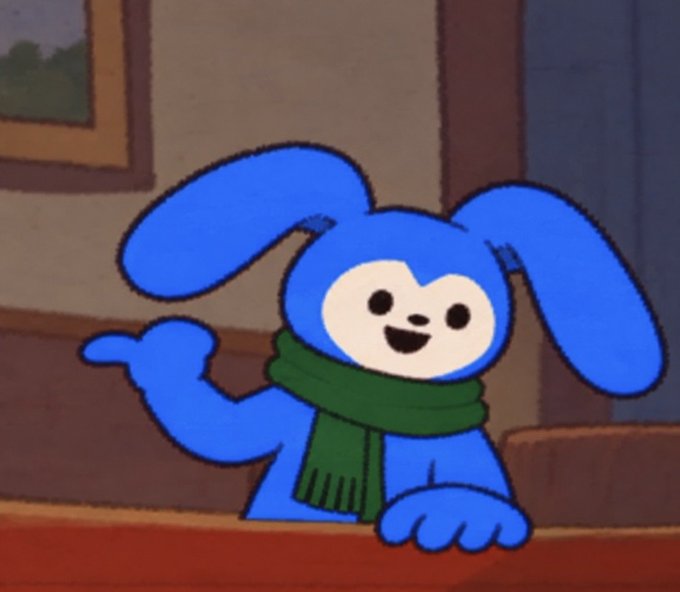 A cartoon screenshot of a blue bunny-like character wearing a green scarf, smiling and gesturing from a cartoon living room setting.
