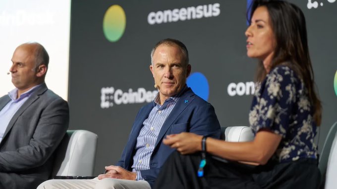 Ripple executives sit on a panel at the Consensus conference (with "consensus" and "CoinDesk" logos visible), where RLUSD's rapid growth to a $2.4B supply and Ripple's $1B GTreasury acquisition are being discussed as the company eyes Europe's MiCA-regulated market next.