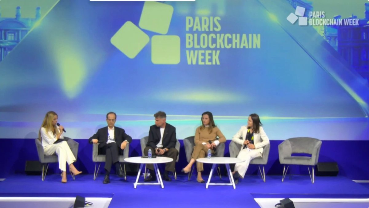 The image features a group of five people sitting around a table at an event, possibly a conference or panel discussion. They are engaged in conversation, with one person speaking while others listen attentively. The setting appears to be indoors, as indicated by the presence of chairs and a dining table. A large screen is visible behind them, which could be used for presentations or visual aids during their discussions.

The image also contains text that reads "XRPL Commons' @Odelia Torteman just said the quiet part out loud at Paris Blockchain Week on-chain credit is the future an upcoming lending amendment will enable undercollateralized lending NATIVELY on the XRP Ledger, aggregating XRP, RLUSD and more the validator vote on". This text seems to be related to the event they are attending or discussing.