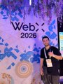 A blurry photo shows two people standing on a stage with a "WebX 2026" backdrop.