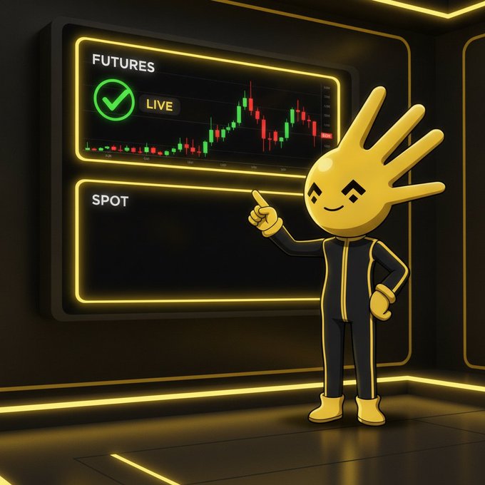 A yellow cartoon mascot with a hand-shaped head stands pointing toward two glowing Binance trading panels—one labeled "FUTURES LIVE" displaying an active candlestick chart, and another labeled "SPOT" that remains empty—visually emphasizing the post's point that everything is in place for the project except the missing spot listing on Binance.