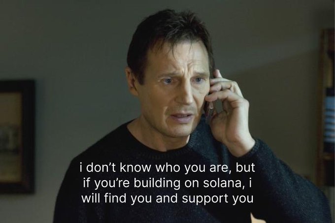 The image features a man talking on his cell phone, with text overlaying the scene that reads "I don't know who you are, but if you're building on Solana, I will find you and support you." The background of the image is white, which contrasts with the black shirt worn by the man.