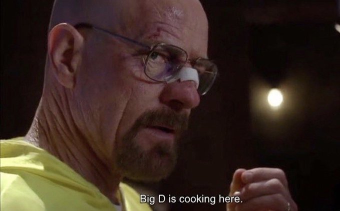A close-up of Walter White from Breaking Bad wearing yellow clothing and glasses, with the subtitle reading 'Big D is cooking here.'