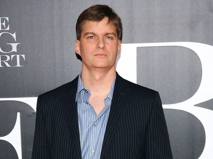 A man in a dark pinstripe suit and blue striped shirt stands in front of a backdrop with partial text reading "E," "G," "RT" and large letter "R" visible. The image appears unrelated to the cryptocurrency giveaway post, likely included as a recognizable figure to attract attention or lend credibility to the engagement-driven promotion.