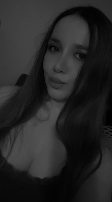 Black and white selfie of a young woman with long hair wearing a dark top.