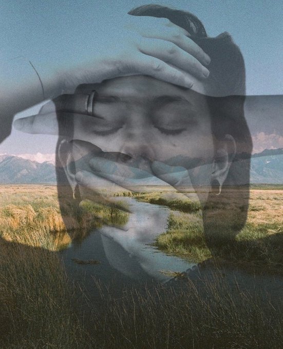 A double exposure photograph blends the serene, closed-eye face of a person with a landscape featuring mountains, sky, and grassy wetlands.