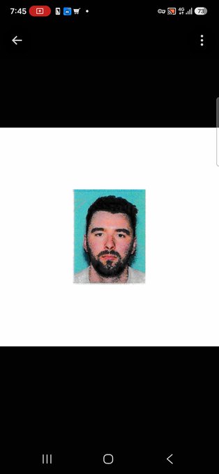 A mobile phone screenshot showing a pixelated portrait of a man with a beard against a blue background, displayed in a gallery viewer.
