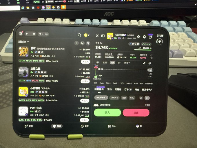 A tablet on a desk displays a Chinese-language crypto trading app with token listings, market charts, and a panel showing “市值 $4.76K” and “24H +4.80K%.”