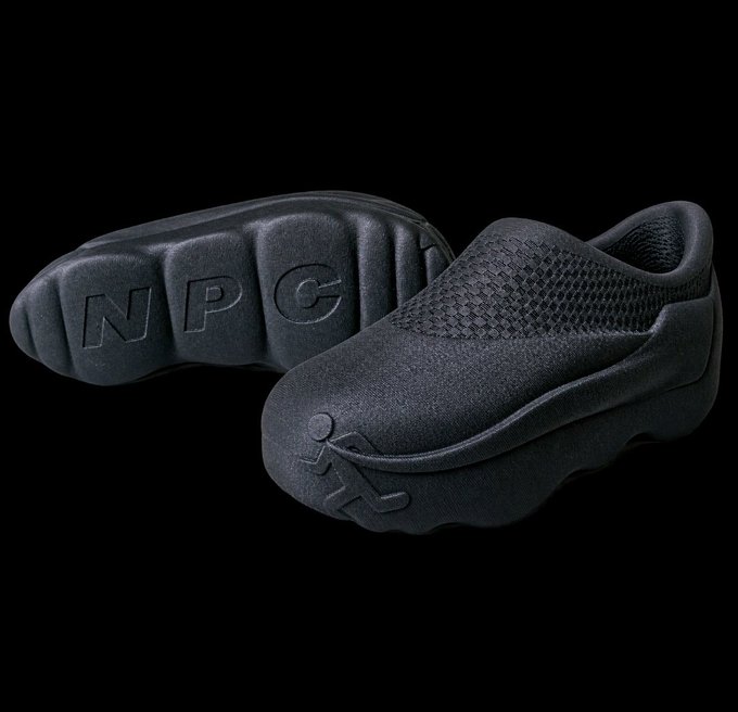 A pair of black NPG slip-on shoes is displayed on a black background, with 'NPG' and a stick figure logo visible on the soles.