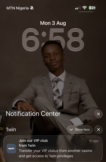 A lock screen on an iPhone displays a young man in a gray suit and tie, with the time 6:58 on Monday, August 3rd and a battery at 82%. A 1win notification invites the user to join their VIP club by transferring VIP status from another casino, which directly connects to the post's excitement about receiving this notification as the start of the new week and their focus on the 1win VIP Club.