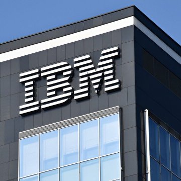 The corner of a dark office building displays large white IBM letters above blue-tinted windows.
