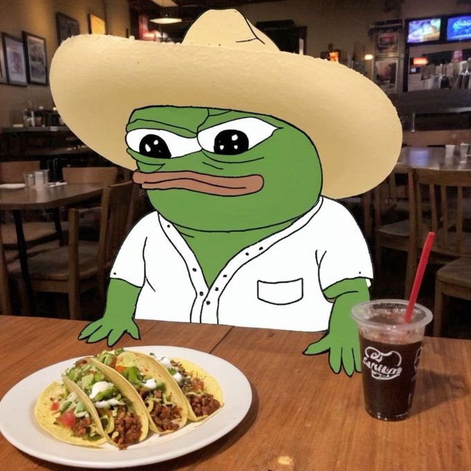 A digitally edited image places the cartoon character Pepe the Frog, wearing a sombrero and white shirt, at a Mexican restaurant, sitting behind a plate of three tacos and a drink in a cup with a red straw.