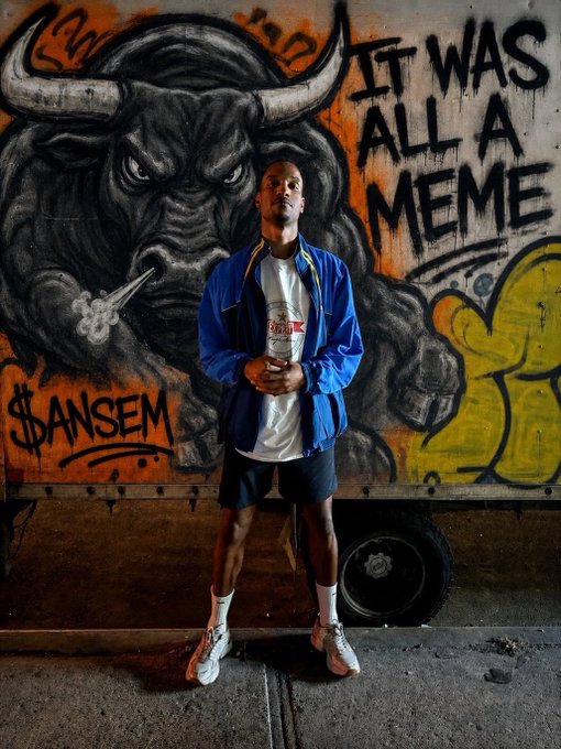 A man stands in front of a vibrant graffiti mural featuring a charging bull and the bold text "IT WAS ALL A MEME" alongside "$ANSEM," visually reinforcing the post's tongue-in-cheek declaration that $ANSEM has reached a $10 billion meme status.