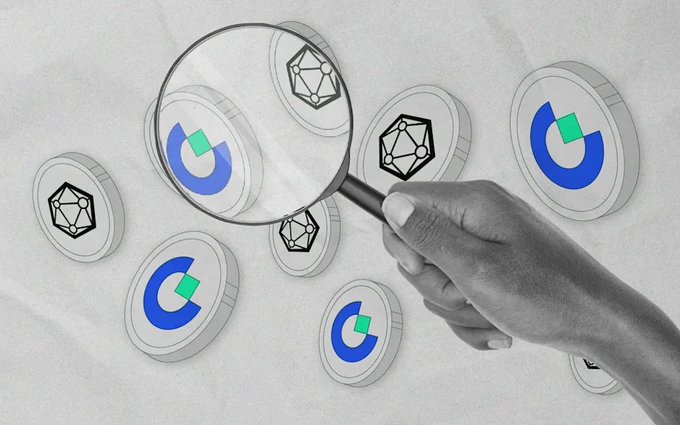 A hand holding a magnifying glass over various cryptocurrency coin icons (including geometric and blue 'C' logos) scattered on a crumpled white paper background.