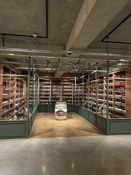 An elegant wine cellar with floor-to-ceiling racks of bottles under warm lighting, featuring a central branded barrel. The post mocks crypto investors for aspiring to such luxury, suggesting they instead settle for cheaper alternatives.