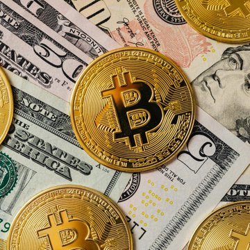 Golden Bitcoin coins rest atop U.S. fifty-dollar bills, symbolizing the intersection of cryptocurrency and traditional currency. The image visually reinforces Strike's new Bitcoin-backed loan offering, highlighting how digital assets like BTC are now being leveraged as collateral in the traditional financial system.