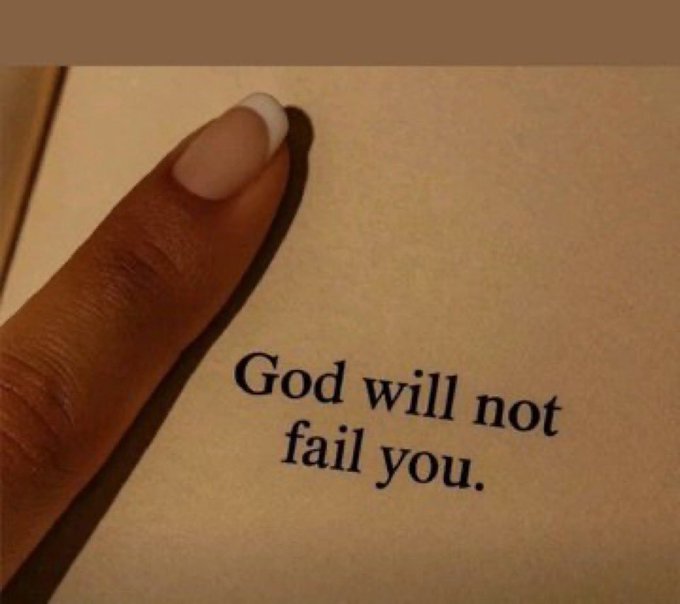 A finger points to an inspirational passage in a book that reads, 'God will not fail you.'