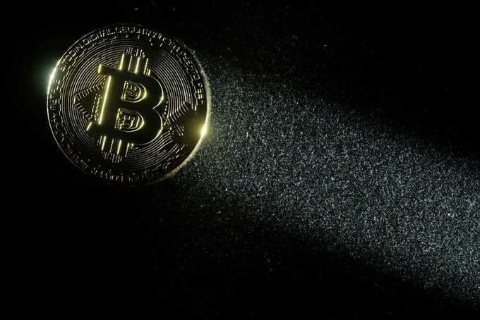 A gold Bitcoin coin with light streaks emanating from it against a dark background, displaying the 'B' cryptocurrency logo.
