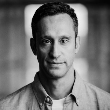 A black-and-white portrait of a man wearing a button-up shirt with a slight smile, photographed against a blurred background. His calm, confident expression contrasts with the post's cynical commentary about the inevitable cycle of speculative pump-and-dump "shitcoins" in crypto markets.