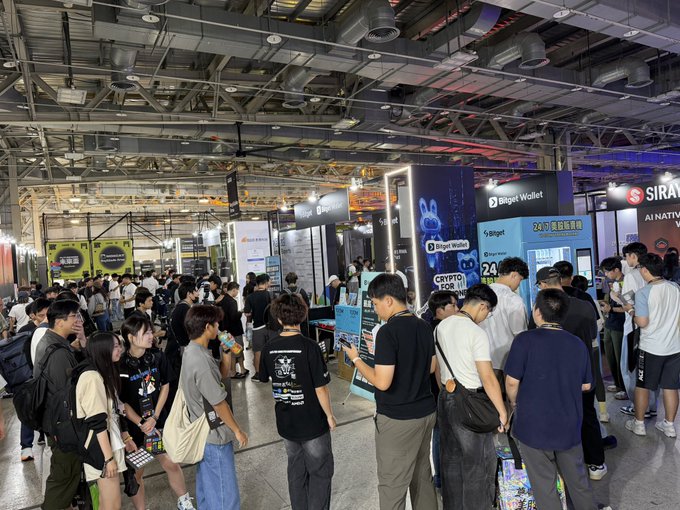 A crowded indoor convention or expo hall where attendees gather around booths for BingX, BingX Wallet, and Sirat AI, with various banners and displays visible.