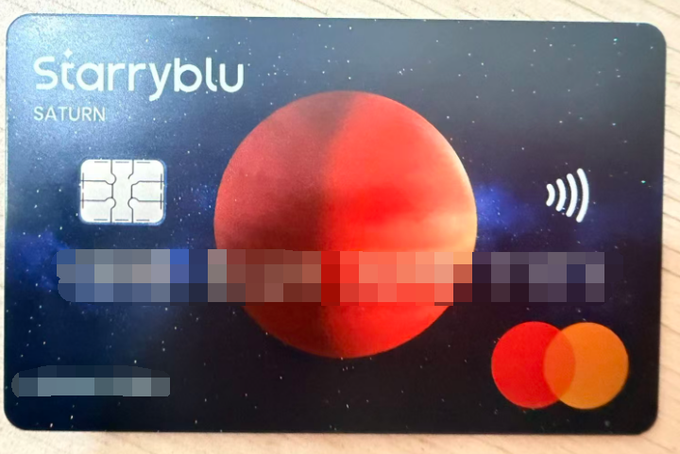 The new Starryblu "SATURN" card, featuring a Mastercard logo and contactless payment symbol, is shown here. This image visually represents the arrival of the card mentioned in the social media post.
